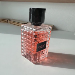 Admiration Eternal parfym - Säljer en parfymflaska från Admiration Eternal med rosa vätska. Flaskan är fyrkantig med rutmönstrad yta och har en stor svart, åttakantig kork. Etiketten är svart med guldtext. Perfekt för dig som gillar snygg design och fräscha dofter.