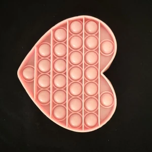 Rosa hjärtformad pop it-leksak - Säljer en rosa pop it-leksak i form av ett hjärta. Perfekt för att stressa ner eller bara ha kul. Gjord i mjuk silikon och har flera bubblor att trycka på.