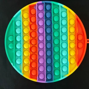 Rund regnbågsfärgad pop it-leksak - Säljer en rund pop it-leksak i regnbågens alla färger. Den är tillverkad i mjuk silikon och har bubblor att trycka på för en avslappnande känsla. Perfekt för att sysselsätta händerna eller minska stress.