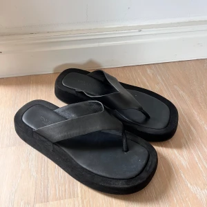 Svarta sandaler med bred rem - Flipflops ifrån Tony Bianco i mocka, fåtal gånger använda. 