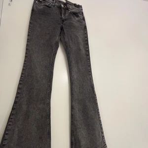 Grå bootcut jeans - Säljer ett par grå bootcut jeans med klassisk femficksdesign och svarta sömmar. Jeansen har en snygg utsvängd passform nertill och normal midja. Knappt använda💞