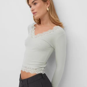 Gina tricot topp - Snygg ljusgrön långärmad topp med v-ringning och spetsdetaljer vid halsringning och nederkant. Använd endast en gång, säljer då jag inte riktigt tyckte den passade mig.