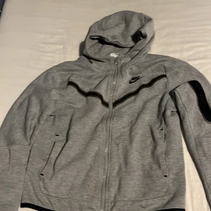 Grå hoodiejacka från Nike - Säljer en grå Nike tech kofta. Ganska bra skick, har ficka på armen och på båda sidorna.