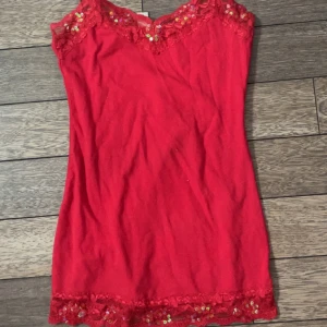 Linne med paljetter och spets! - Säljer ett rött linne från Bozzolo med vackra spetsdetaljer och paljetter vid halsringningen och nertill. Linnet har smala band, tillverkat i en mjuk bomullsblandning för extra komfort. 