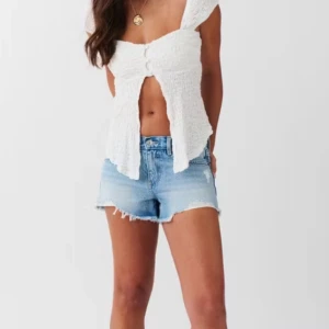 Ljusblå jeansshorts - Säljer ett par ljusblå jeansshorts från Gina Tricot med råa fransade kanter och slitningar framtill. Klassisk femficksmodell med knapp och dragkedja. Perfekta för sommaren och ger en avslappnad look.