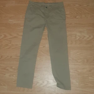 Beige chinos från Hampton Republic - Säljer ett par beige chinos från Hampton Republic i slim fit-modell. Byxorna har normal midja, knapp och dragkedja framtill samt fickor på sidorna och baktill. Perfekta för en stilren och avslappnad look.