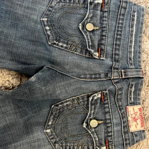 Jeans från True Religion - Säljer dessa snygga true religon jeans som är köpta i NEW YORK❤️ i storlek 27 och 84cm i innebenslängd! Det finns ett litet igensytt hål som man ser på bilden men inget som syns när man har på sig dom! har tecken på användning längst ner vid jeansen och vid knappen!❤️😊