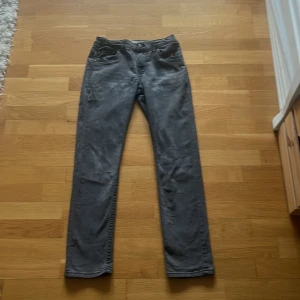 Grå jeansbyxor Levis 512 - Säljer ett par grå Levis 512 jeans med klassisk femficksdesign och rak passform. Byxorna har normal midja och Levis-logga på bakfickan. Perfekta för dig som gillar stilrena och tidlösa jeans.