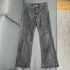 Svarta bootcut jeans högmidjade - Säljer ett par svarta bootcut jeans med klassisk femficksdesign och dragkedja. Jeansen har en något utsvängd passform nertill och är tillverkade i denim. Perfekta för dig som gillar en retrostil.