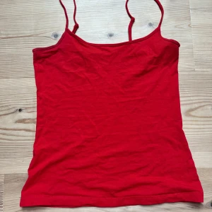 rött linne - En enkel och stilren röd linnetopp med smala axelband. Perfekt att bära under varma dagar eller som lager under en skjorta. Tidlös design som passar till mycket.