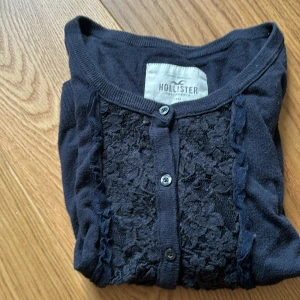 Svart kofta med spets från Hollister - Mysig svart/blå kofta från Hollister med knappar 