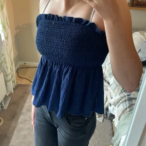 Mörkblå smockad linnetopp - Säljer en mörkblå linnetopp med smockad överdel och volangkant upptill. Toppen är ärmlös och har en luftig, lätt utsvängd passform nedtill. Köpt från SHEIN och knappt använd, storlek S. Pris kan diskuteras💕💕