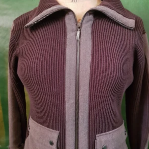 Brun ribbad jacka med dragkedja - Säljer en brun ribbad jacka med grå detaljer och dragkedja framtill. Jackan har två stora fickor med knappar och en markerad krage. Perfekt för dig som gillar en stilren och bekväm look.