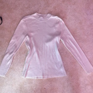 Vit ribbad långärmad tröja från H&M - Säljer en vit ribbad långärmad tröja från H&M i storlek L. Tröjan har en högre rund halsringning och är figurnära i modellen. Perfekt att styla med jeans eller kjol för en enkel och stilren look. Har en fin passform där den är lite tajtare runt midjan. 