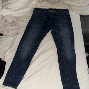 Mörkblå jeansbyxor från Denim & Supply Ralph Lauren - Säljer ett par mörkblå jeansbyxor från Denim & Supply Ralph Lauren. Klassisk femficksmodell med raka ben och snygga slitningar. Jeansen har normal passform och är tillverkade i bomull med en liten mängd stretch för extra komfort.