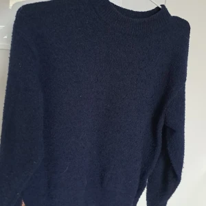 Mörkblå stickad tröja - Mysig mörkblå stickad tröja med rund halsringning och långa ärmar. Tröjan har en enkel och klassisk design med ribbade muddar vid hals, ärmslut och nederkant. Den är lite nopprig men inget man märker av särskilt mycket. Från gina young I storlek 146-152 men funkar nog för folk med 158-164 också. Pris kan diskuterasss🎉🎉🍾❤️