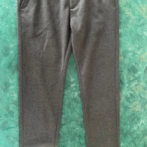 Grå kostymbyxor  - Säljer ett par klassiska grå kostymbyxor  med snygga detaljer som knapp och dragkedja framtill samt fickor både fram och bak. Byxorna har en rak passform och diskret Burberry-mönster på insidan av linningen.
