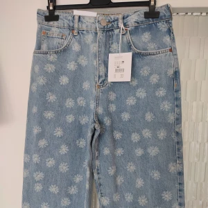 Ljusblå jeans med mönster i storlek 27/32 - Ljusblå jeans med mönster i storlek 27/32. Jeans modellen heter Never Denim JP 90's Straight Flower. Jeansen är gjorda av 100% bomull. Helt nya med alla lappar kvar. Nypris på dessa är 599kr.