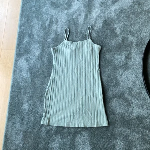 Ljusgrön ribbad klänning från SHEIN - Säljer en ljusgrön ribbad klänning från SHEIN med smala axelband och rak halsringning. Klänningen är kort och har en enkel, stilren design som passar perfekt till sommaren.