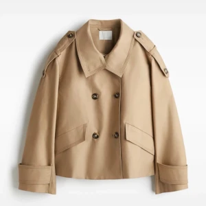 Beige kort trenchcoat från H&M - I storlek S och använd en gång. Helt slutsåld och jätte efterfrågad. Inga defekter så gott som ny!