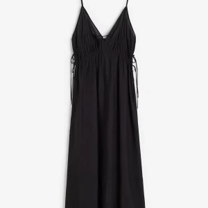 Svart långklänning med smala axelband - Säljer en svart långklänning med smala axelband och v-ringad hals. Klänningen har en avslappnad passform och knytning i sidorna vid midjan för extra detalj. Perfekt för sommarens alla tillfällen. 