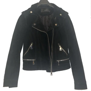 Svart mockajacka från Vero Moda - Ordinariepris för jackan är ca. 1549kr. Säljer en svart mockajacka från Vero Moda med silvriga dragkedjor och detaljer. Jackan har snedställd dragkedja framtill, fyra fickor med dragkedja och långa ärmar. Snygg bikerstil som passar perfekt till många outfits.