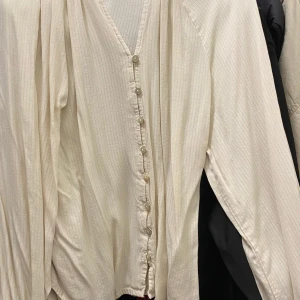 Beige blus med v ringning och knappar - Säljer en stilren beige blus med v-ringning och knappar framtill. Perfekt för dig som gillar en enkel men elegant look.
