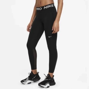 Nike Pro svarta leggings med mesh - Svarta Nike Pro leggings med hög midja och bred resår med logga. Tight passform och meshpaneler längs benen för extra ventilation. Perfekta för träning och riktigt snygga till sneakers. Tillverkade i stretchigt syntetmaterial.