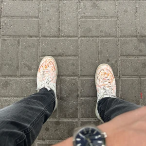 Maison margiela orange paint splatter  - Maison Margiela sneakers i vitt skinn med unika orange och rosa färgstänk över hela skon. Klassisk rund tå, snörning och den ikoniska Margiela-tungan med logotyp. Snygg och konstnärlig vibe, perfekt för dig som gillar statement pieces. 40 men passar solklart 41.