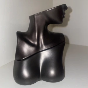 Parfymflaska i form av kvinnokropp - Unik parfymflaska i svart metallic, formad som en stiliserad kvinnokropp med markerad hals, axlar och byst. Flaskan har en matt finish och är tillverkad i glas och metall. Perfekt som statement-piece på sminkbordet eller i samlingen.
