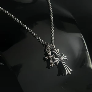 Rebel Double Cross Necklace - Halsband med två kors i stilfull kontrast. Kedjan är ca 60 cm och kan justeras genom att fästas var som helst längs dess längd.