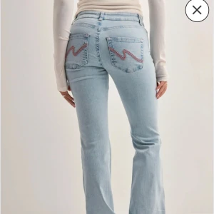 Ljusblå bootcut jeans med brodyr - Säljer ett par lågmidjade ljusblå jeans med bootcut design från nelly. Använda en gång. 