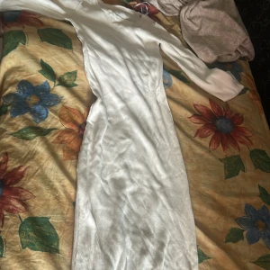 Vit ribbad långklänning från H&M - Säljer en vit ribbad långklänning från H&M med lång ärm och snygg v-ringning. Klänningen är figurnära och har en stilren look som passar perfekt när du vill känna dig extra snygg. Materialet är mjukt och stretchigt för en bekväm känsla.