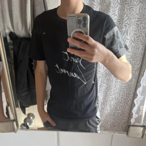 Svart Saint Laurent t-shirt - Svart t-shirt från Saint Laurent med vit handskriven logga på framsidan. Klassisk passform och korta ärmar, perfekt för en clean och stilren look. Skriv för fler bilder och kom gärna med prisförslag 