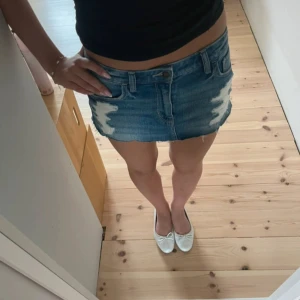 Blå jeanskjol från Hollister - Säljer en blå jeanskjol från Hollister med slitna detaljer och rå kant. Kjolen är kort, har klassiska fickor och bälteshällor. Perfekt för dig som gillar en avslappnad och trendig stil.