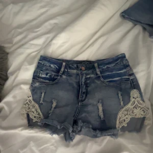 Blå jeansshorts med spetsdetaljer - Snygga blå jeansshorts med spets. Köpta från RUT&CIRCLE för 450kr. De sitter lågmidjat på. 