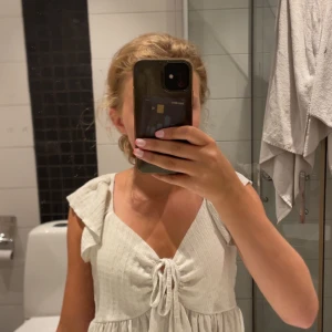 Vit topp/blus från lager 157 - Supersöt vit blus  från 157 med volangärmar och knytning framtill. Blusen har en lätt rynkad struktur och v-ringning, perfekt för varma dagar. Luftig och flowy modell som ger en chill vibe.