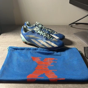 Blå adidas fotbollsskor med väska - Säljer nu mina ADIDAS X CRAZYFAST + FG MARINERUSH - Blå/ Vit/ Röd. Anledningen till försäljningen är att jag inte använder skorna längre. Skorna fortsatt i mycket bra skick. Finns ytterst lite slitage på bägge skorna vid tårna. Pris 1450 kr, lägg ett bud så kan vi diskutera pris!( kund står för frakt). Passar de flesta fötterna och har en tight on- foot-feeling. 