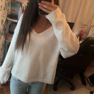 Vit stickad v-ringad tröja 157 - Mysig vit stickad tröja från 157 med v-ringning och långa ärmar. Tröjan har en relaxed fit och ribbade muddar vid ärmslut och nederkant. Perfekt att slänga på sig när det är kyligt ute. Jag köpte den i storlek M men gillar hur den passar eftersom den känns mer som S och ger en lite oversized look. 