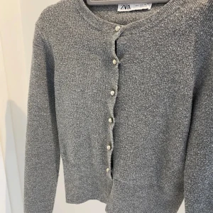 Grå kofta från Zara med pärlknappar - Mysig grå kofta från Zara med rund halsringning och snygga pärlknappar framtill. 
