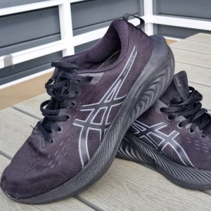 Svarta Asics sneakers strl 38 - Snygga svarta Asics sneakers med grå logga på sidorna och svart snörning. Ovandelen är i mesh-liknande syntetmaterial och sulan är rejäl och mönstrad för bra grepp. Perfekta för träning eller vardagsstil. Modell: Gel-Excite 10  Löpskor / Träningsskor, ok skick, använda mest inomhus  Storlek 38 (24,0 cm)