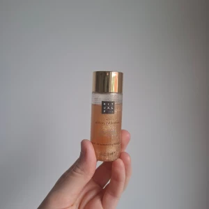 Rituals The Ritual of Karma Shimmer Oil - Shimmering body oil från Rituals (The Ritual of Karma). Kommer i en genomskinlig plastflaska med guldigt lock och innehåller 30 ml. Oljan är gyllene med massor av fina glitterpartiklar som ger huden en snygg glow. Perfekt för att boosta lystern på kroppen. Kom i ett kit men har inte kvar resten av kitet och oljan är aldrig använd. 