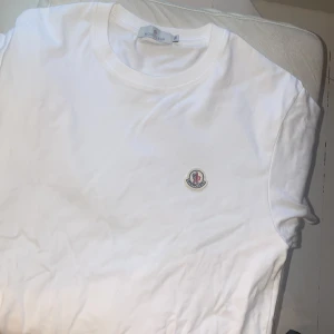 Vit Moncler t-shirt kvitto finns - Clean vit t-shirt från Moncler i bomull med klassisk rund hals och broderad logga på bröstet. Enkel och stilren design som passar till allt. Perfekt för dig som gillar exklusiva basics och vill ha en snygg logga på bröstet.