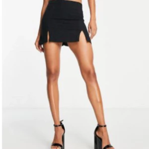 Svart minikjol med slits - Svart kortkjol med två snygga slitsar framtill. Kjolen har en tight passform och är perfekt för dig som gillar en stilren och trendig look. Enkel att matcha med crop tops eller oversized jackor.