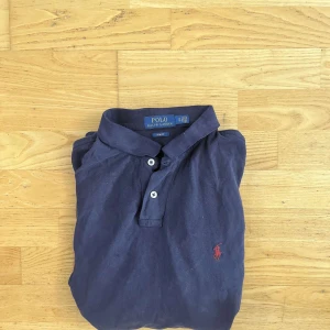 Mörkblå pikétröja från Ralph Lauren - Klassisk mörkblå pikétröja från Polo Ralph Lauren i slim fit-modell. Står XL men skulle säga att den sitter som mellan M och L eftersom det är slimfit.