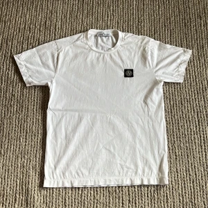 Vit Stone Island t-shirt - Vit t-shirt från Stone Island i bomull med klassisk rund hals och korta ärmar. Skick: 10/10, Skickar inom 1 dag