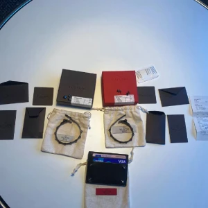Svarta Valentino armband med nitar - Två svarta armband från Valentino Garavani i läder med ikoniska pyramidformade nitar i silverfärg. Snygg och edgy design som ger en cool vibe till din outfit. Kommer med originalpåsar och boxar från Valentino.