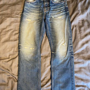 Nudie jeans sleepy sixten  - Ett par riktigt schyssta nudie jeans av modell sleepy sixten. Ljusblå tvätt med fabriksgjorda slitningar, whiskers och honeycombs! Har en straight/relaxed passform. Aningen stor i storleken, Sitter mer som en 32/32. tillverkade i Italien. Mer eller mindre oanvända                                                                  Skriv om ni har några funderingar!                                         //Hugo