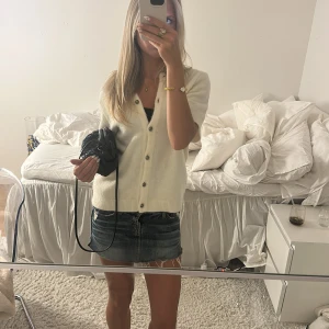 Vit kofta med kort ärm och knappar - Superfin vit kofta med korta ärmar och snygga knappar framtill. Koftan är stickad och har en v-ringad design som ger en chill och trendig vibe. Perfekt att slänga över ett linne eller t-shirt för en enkel men stilren look. Storlek L man passar mig som har xs-s jättebra🩷