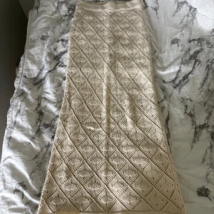 Krämvit stickad långkjol med mönster - Superfin krämvit långkjol i stickat material. Kjolen har en mjuk och elastisk midja. Den är knappt använd och därför säljs den💞